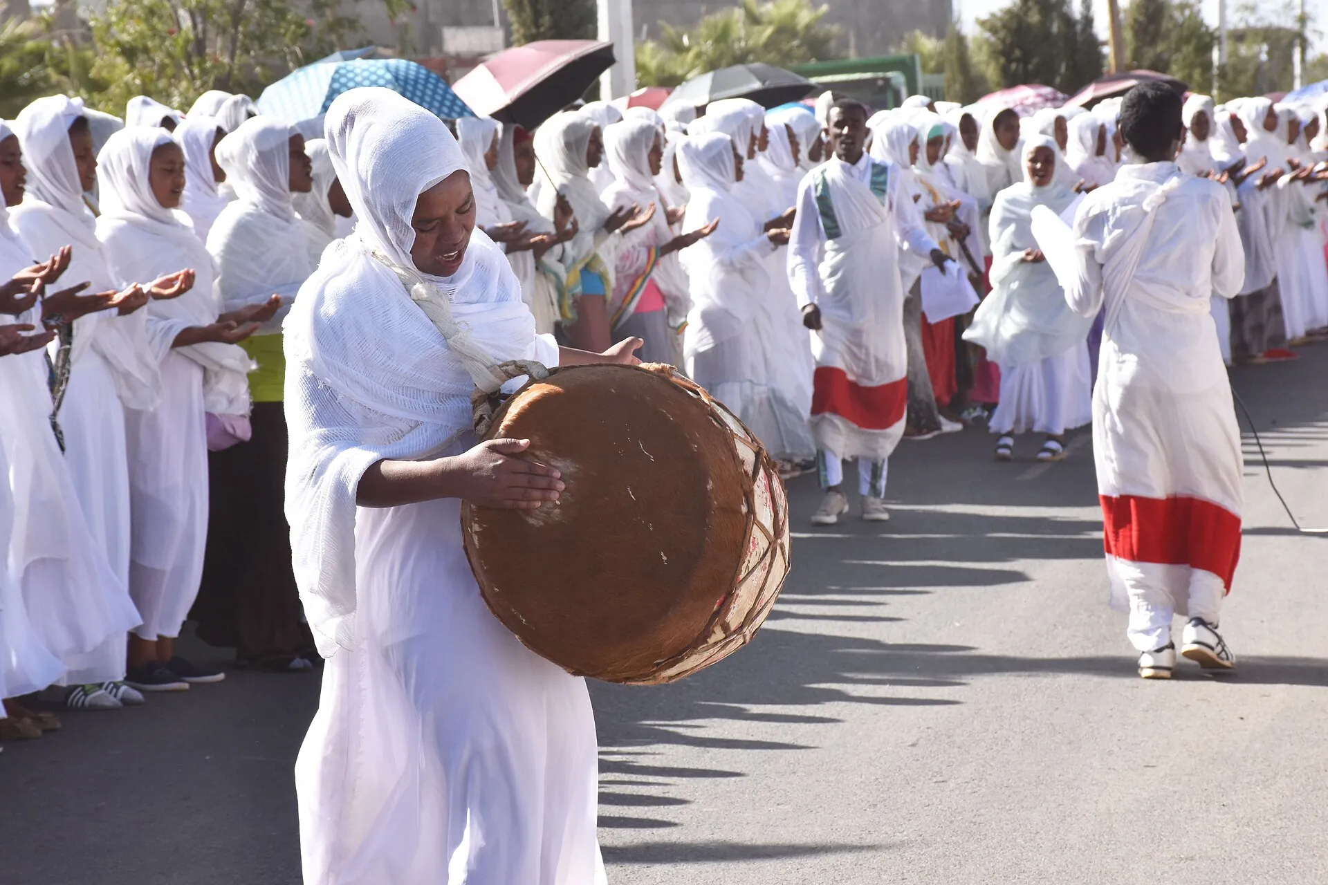 Worshippers in white shawls at an Ethiopian Epiphany procession, one carrying a drum.