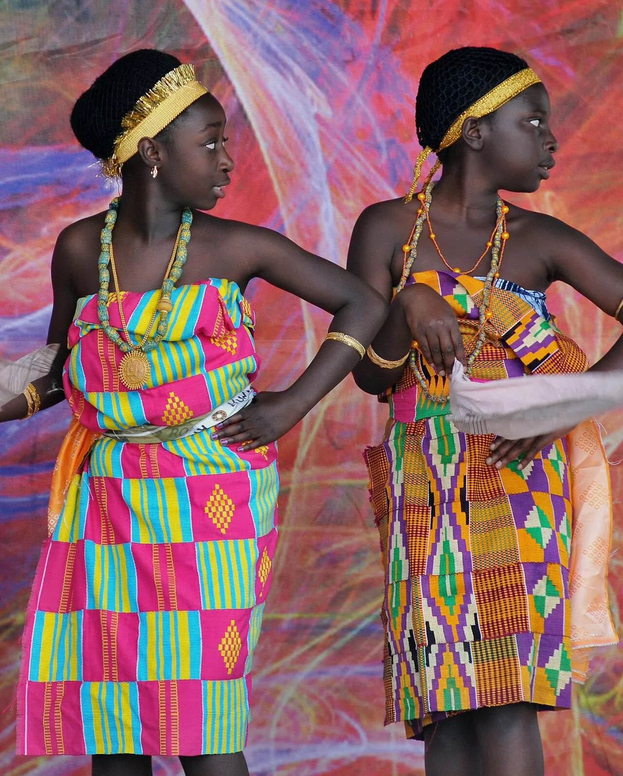 Two Akan dancers from Ghana in kente wraps and beaded headbands.