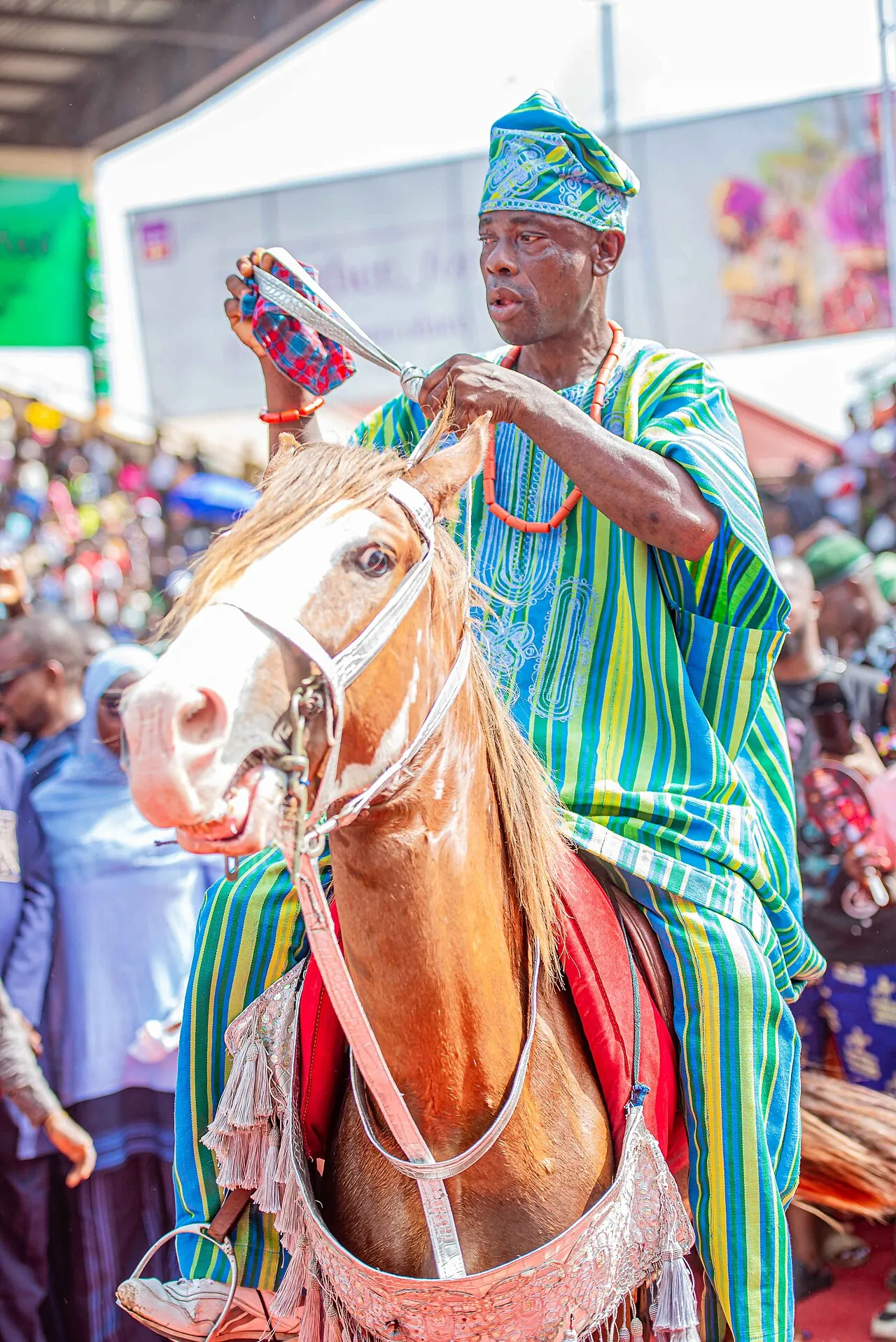 A horseman at Ojude Oba in green and white striped aso-oke and a matching cap.